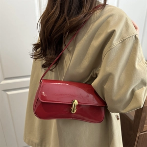 Glossy red patent leather underarm bag with gold metal buckle shown on a model