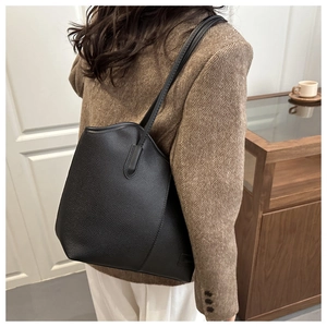 Detail of black pebbled leather tote bag with subtle logo embossing and slim shoulder straps