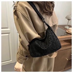 Detail showing high-quality leopard print hobo bag with gold buckle on a trench coat