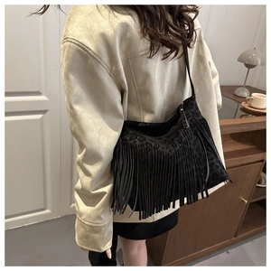 Detail of black bohemian tassel shoulder bag with subtle leopard print pattern