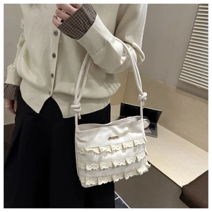 Detail of cream lace small square bag featuring multi-layer lace trim and knotted strap