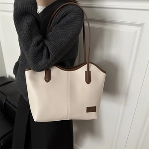 Large capacity vintage cream tote bag with brown trim shown on model against white wall