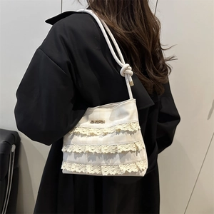 Chic beige lace tote bag with knotted shoulder strap worn with a black wool coat