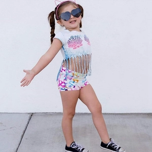 Detail of girl's summer set featuring tie-dye tassel t-shirt and printed shorts