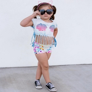 Close-up of girl summer outfit with shell print fringe top and colorful patterned shorts