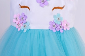Détail de robe licorne avec appliques florales, perles et jupe en tulle bleu