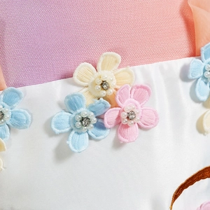 Dettaglio macro di fiori 3D con perle e paillettes sull'abito da principessa unicorno in tulle