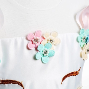 Détail d'appliqués floraux 3D avec perles sur une robe de fête licorne blanche