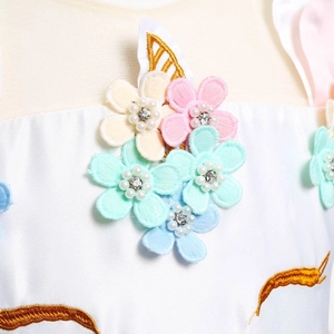 Détail de broderie licorne avec fleurs 3D et perles sur robe en satin blanc fille