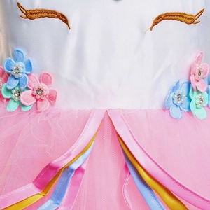 Détail d'une robe licorne fille avec broderies dorées et fleurs 3D appliquées