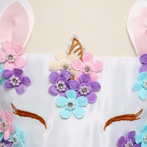 Dettaglio vestito da unicorno con fiori 3D, perline e ciglia ricamate su bianco