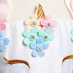 Détail de broderie licorne avec fleurs 3D pastel et perles sur robe en satin blanc