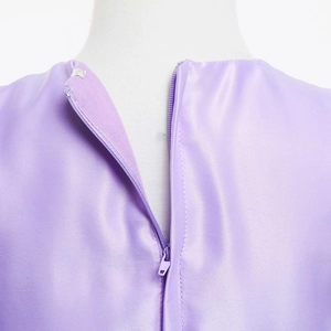Détail de la fermeture éclair invisible et du satin violet brillant de la robe fille