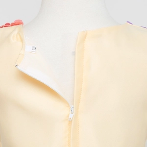 Dettaglio dell'abito da principessa giallo con fiori sullo scollo e etichetta taglia 120