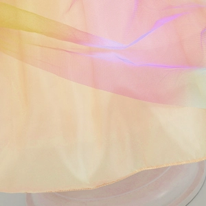 Dettaglio macro del tessuto in tulle arcobaleno multistrato con sfumatura rosa e gialla