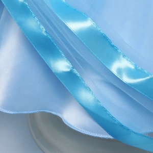 Dettaglio della gonna in tulle azzurro con nastro di raso e finiture a strati leggeri