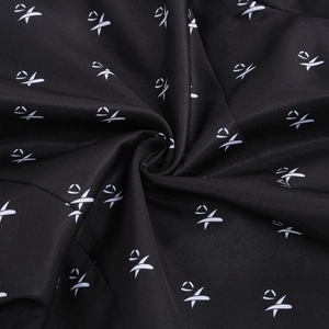 Close-up of black fabric texture with white XO print patterns for the Wednesday dress