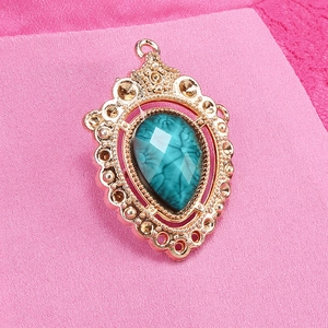 Vintage gold Victorian-style turquoise pendant on a pink knitted fabric background