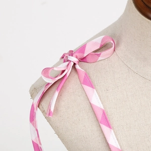 Detailed view of pink and white checkered shoulder strap tied in a bow on a dress