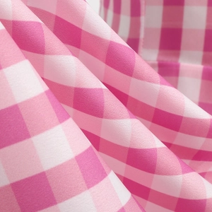 Detailed macro view of pink and white checkered fabric texture with soft natural pleats