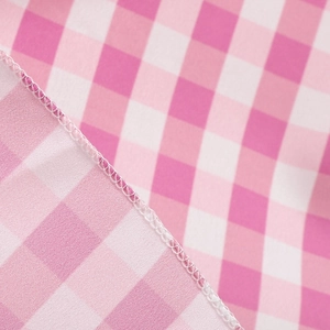 Detail of pink and white gingham fabric with neat overlock stitching on the dress edge