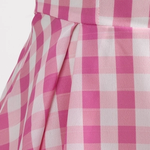 Detailed view of pink gingham dress featuring pleated waistline and woven fabric texture