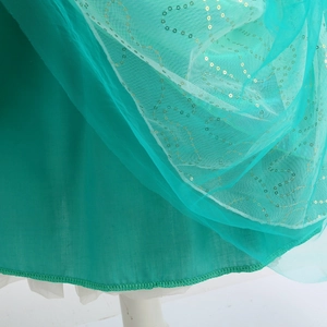 Détail du tissu en tulle vert d'eau avec paillettes dorées et coutures de précision