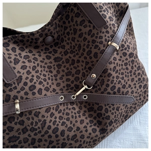 Gros plan du sac cabas léopard montrant la texture suédée et les boucles métalliques dorées