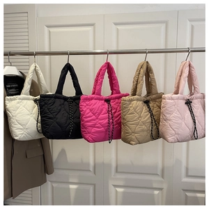 Detail of five heart-quilted drawstring tote bags in white, black, pink, and khaki colors