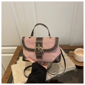 Close-up of pink suede handbag with brown leather trim and large gold ring buckle