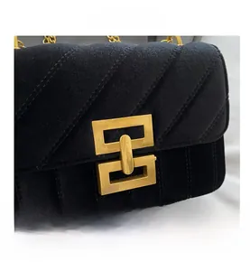 Close-up of black velvet quilted chain bag with vintage gold geometric twist lock