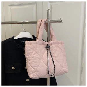 Detailed close-up of pink heart-quilted tote bag with black drawstring and fluffy texture