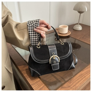 Detail of vintage black suede handbag with gold buckle and contrast stitching