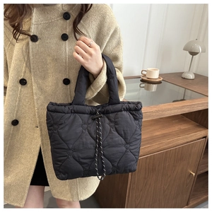 Detail showing heart quilted nylon tote bag with drawstring closure on model arm