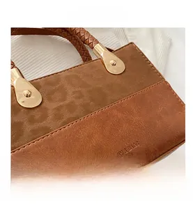 Detail of vintage brown leather bag showing frosted texture and gold teardrop metal hardware