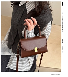 Detailed view of deep brown leather crossbody bag with a gold metal clasp and stitching