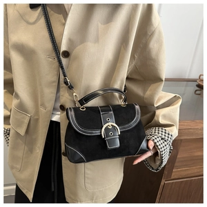 Detail of a retro black suede and leather handbag with contrast stitching on a blazer