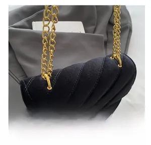 Close-up of black velvet quilted handbag with elegant gold metal chain and logo clasp