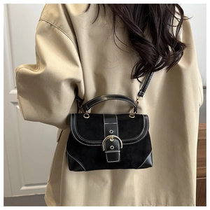 Detail of vintage black bag featuring white contrast stitching and golden horseshoe buckle