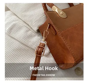 Detailed macro view of golden hardware hook and textured brown leather on vintage handbag