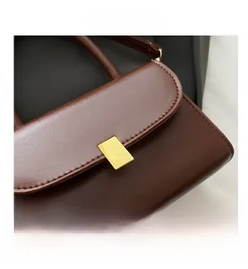 Close-up of dark brown leather handbag with elegant rectangular gold metal clasp