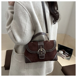 Close-up of a vintage dual-texture leather handbag worn by a model in a cozy office setting