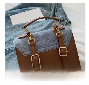Detailed view of the gold-tone metal hook and denim patchwork on a brown leather bag