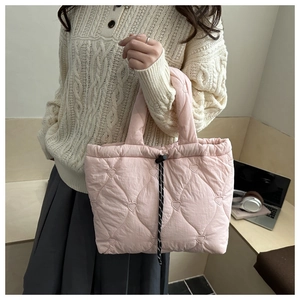Detail of pink quilted tote bag with heart embroidery and functional drawstring closure