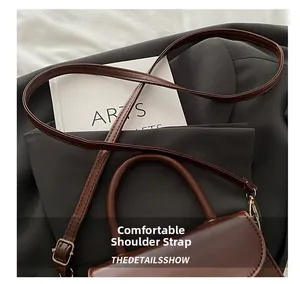 Detail view of the brown leather shoulder bag featuring an adjustable strap and metal buckle