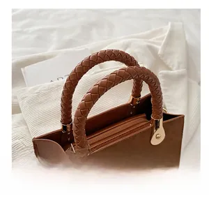 Close-up of brown PU leather bag featuring woven top handle and gold metal hardware