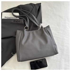 Detail of dark grey textured tote bag with gold ring buckle and shoulder strap