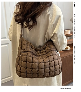 Détail du sac cabas matelassé marron porté à l'épaule sur un long manteau beige