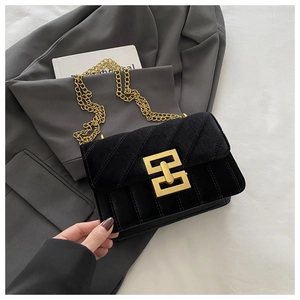 Close-up of black velvet crossbody bag with golden chain and metallic geometric clasp