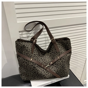 Détail du sac cabas léopard montrant les anses en cuir et les boucles dorées